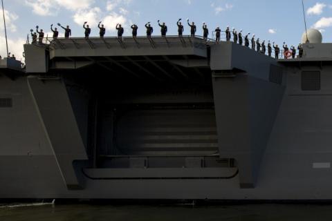 Sailors wave from the deck of the Izumo warship as it departs from the harbour of the Japan United Marine shipyard in Yokohama, south of Tokyo, March 25, 2015. REUTERS/Thomas Peter