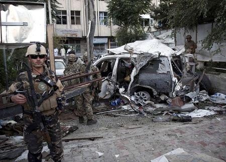 Afghan security personnel (L) keeps watch next to a damaged car belonging to foreigners, after a bomb blast in Kabul, Afghanistan, August 22, 2015. PHOTO BY REUTERS/Ahmad Masood