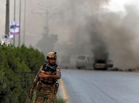 A member of Afghan security forces stands near the site of an attack as smoke billows, near the Afghan parliament in Kabul, Afghanistan, June 22, 2015. PHOTO BY REUTERS/Ahmad Masood