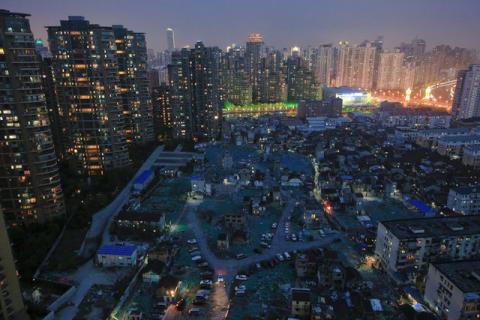 A night view of the old houses surrounded by new apartment buildings at Guangfuli neighbourhood in Shanghai, China, April 10, 2016. PHOTO BY REUTERS/Aly Song