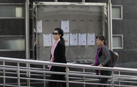 Singer Meng Ge (L) walks into a court ahead of a verdict hearing of her son in Beijing