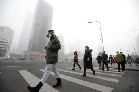 A man wearing a respiratory protection mask walks toward an office building during the smog after a red alert was issued for heavy air pollution in Beijing's central business district, China, December 21, 2016. PHOTO BY REUTERS/Jason Lee