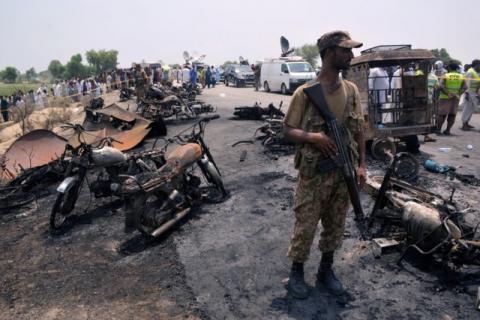 A soldier stands guard amid burnt out cars and motorcycles at the scene of an oil tanker explosion in Bahawalpur, Pakistan, June 25, 2017. PHOTO BY REUTERS/Stringer