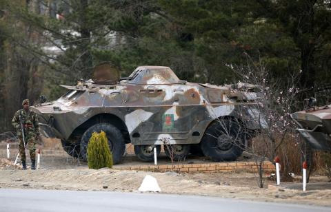 A member of the Lesotho military looks on as he stands guard in front of an armed personnel carrier at the entrance of the army barracks in the capital Maseru