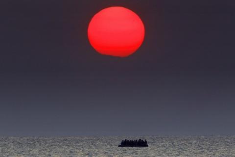 A red sun is over a dinghy overcrowded with Syrian refugees drifting in the Aegean sea between Turkey and Greece after its motor broke down off the Greek island of Kos, August 11, 2015. PHOTO BY REUTERS/Yannis Behrakis