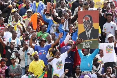 Supporters of Zimbabwe's President Robert Mugabe hold a poster with his picture as he addresses mourners gathered for the burial of National Hero Charles Utete at the Heroes Acre in Harare, Zimbabwe, July 19, 2016. PHOTO BY REUTERS/Philimon Bulawayo