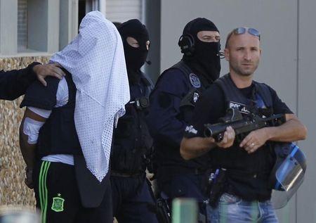 The suspect held over an attack against a gas company site is escorted by police officers during investigations in Saint-Priest, near Lyon, France, June 28, 2015. PHOTO BY REUTERS/Emmanuel Foudrot