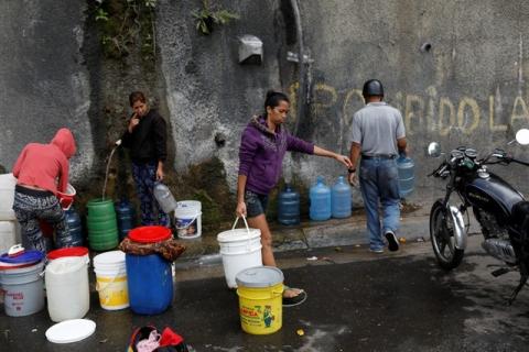 A woman carries a container filled with water coming from a mountain, in a road at Plan de Manzano slum in Caracas, Venezuela, July 20, 2018. PHOTO BY REUTERS/Marco Bell