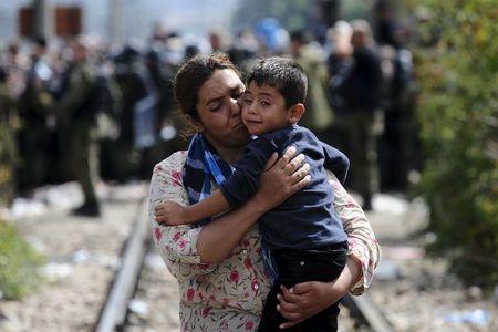 A woman carries a boy after crossing Greece's border into Macedonia near Gevgelija, Macedonia, August 22, 2015. PHOTO BY REUTERS/Ognen Teofilovski