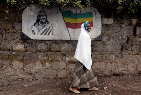 A traditionally-dressed Ethiopian woman walks past a mural depicting Ethiopia's Emperor Tewodros II in Addis Ababa, Ethiopia. PHOTO BY REUTERS/Andrew Heavens
