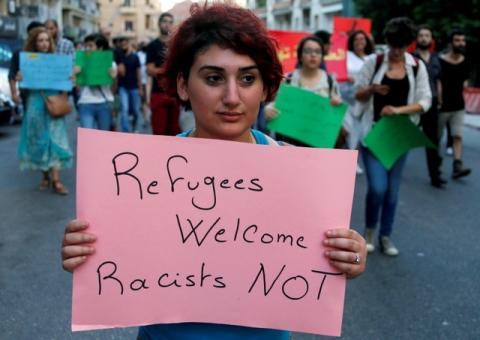 A woman carries a placard during a demonstration against sectarianism, also calling for abolishing curfews put on Syrian refugees in Beirut, Lebanon, July 18 , 2016. PHOTO BY REUTERS/Mohamed Azaki
