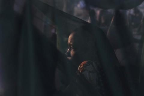 A woman displaced by the fighting in Bor county sits by her mosquito net in the early morning in Minkaman, in Awerial county, Lakes state, in South Sudan, January 15, 2014. PHOTO BY REUTERS/Andreea Campeanu