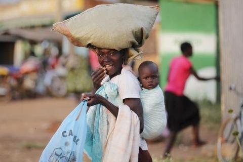 A woman carries a child and a bag on her head within the trading centre of the U.S. President Barack Obama's ancestral village of Nyang'oma Kogelo, west of Kenya's capital Nairobi, July 15, 2015. PHOTO BY REUTERS/Thomas Mukoya