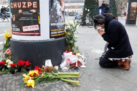A woman prays near the area where a truck which ploughed into a crowded Christmas market in the German capital last night in Berlin. PHOTO BY REUTERS/Pawel Kopczynski