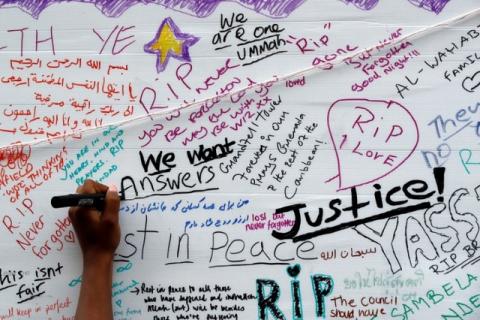 A woman writes on a message wall near the scene of the fire which destroyed the Grenfell Tower block, in north Kensington, West London, Britain, June 15, 2017. PHOTO BY REUTERS/Stefan Wermuth