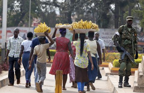 Women carry baskets of banana as they walk past a military personnel patrolling in Uganda's capital Kampala, February 19, 2016. Ugandan police shot in the air and fired tear gas at opposition protesters in several parts of southern Kampala on Friday, a Reuters witness said, after the presidential election a day earlier. PHOTO BY REUTERS/James Akena