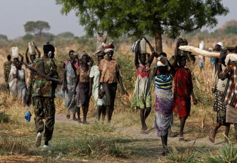 A soldier walks past women carrying their belongings near Bentiu, northern South Sudan, February 11, 2017. PHOTO BY REUTERS/Siegfried Modola