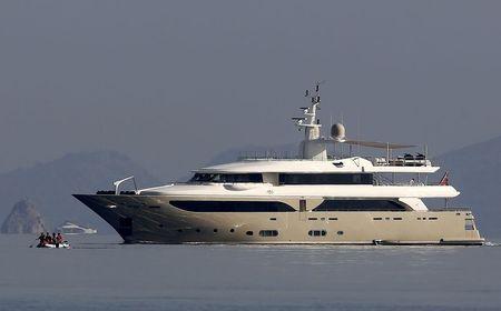 A luxury yacht speeds as Iranian migrants paddle an engineless dinghy trying to cross a part of the Aegean sea from the Turkish coast (seen in the background) to the Greek island of Kos, August 15, 2015. PHOTO BY REUTERS/Yannis Behrakis