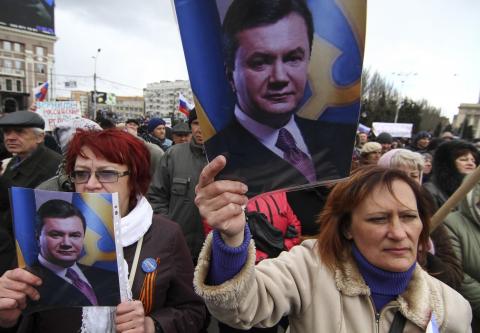 Pro-Russian activists hold pictures of ousted Ukrainian President Victor Yanukovich during a protest in central Donetsk March 29, 2014. Russia said on Saturday it had "no intention" of invading eastern Ukraine, responding to Western warnings over a military buildup on the border following Moscow's annexation of the Crimean peninsula. REUTERS/Stringer