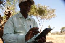 Joseph Ibeere demonstrates how to use a smartphone to gather farm data in Muiri village, central Kenya, on September 18, 2019. PHOTO BY Thomson Reuters Foundation/Kagondu Njagi
