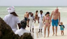 Tourists walk next to beach operators along the shores of the Indian Ocean in the Kenyan coastal city of Mombasa, January 18, 2016. PHOTO BY REUTERS/Joseph Okanga