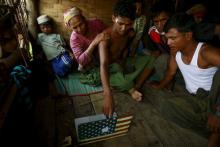 Abdhulami (C), 22, who was released from a human trafficking boat, points at pictures of people he recognises from the boat as he rests at a refugee camp outside Sittwe, Myanmar, May 27, 2015. PHOTO BY REUTERS/Soe Zeya Tun