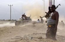 An anti-Houthi fighter of the Southern Popular Resistance stands guard as comrades fire from a tank in Yemen's southern port city of Aden, May 28, 2015. PHOTO BY REUTERS/Stringer