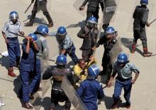 Zimbabwean anti-riot policemen beat up a man as they disperse about 100 people protesting against the central bank's plans to re-introduce local banknotes, in Zimbabwe's capital Harare, August 17, 2016. PHOTO BY REUTERS/Philimon Bulawayo