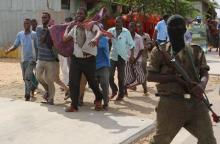Somali people carry the dead body of a victim from the scene of a suicide car explosion in Hodan district in the capital Mogadishu, June 24, 2015. PHOTO BY REUTERS/Feisal Omar