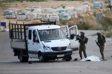 The body of a Palestinian, who the Israeli military said was shot dead by the Israeli troops after he rammed his vehicle into three Israeli soldiers, lies covered on the ground as Israeli soldiers inspect the scene near Beituniya near the West Bank city of Ramallah, May 3, 2016. PHOTO BY REUTERS/Mohamad Torokman