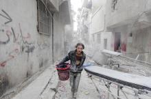 A boy carries his belongings at a site hit by what activists said was a barrel bomb dropped by forces loyal to Syria's President Bashar al-Assad in Aleppo's al-Fardous district, Syria, April 2, 2015. PHOTO BY REUTERS/Rami Zayat
