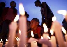 A boy sits next to the lit candles as he takes part in a candlelight vigil, a month after the April 25 earthquake, in Kathmandu, Nepal, May 25, 2015. PHOTO BY REUTERS/Navesh Chitrakar