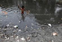 A boy searches for coins thrown by devotees as religious offerings in a polluted water channel near a temple in Kolkata June 5, 2014. Thursday marks this year's World Environment Day. PHOTO BY REUTERS/Rupak De Chowdhuri
