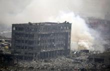 Smoke rises next to a damaged building at the site of the explosions at the Binhai new district in Tianjin, China, August 14, 2015. PHOTO BY REUTERS/Jason Lee