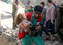 A civil defence member carries a child that survived from under the rubble at a site hit by airstrikes in the rebel held area of Old Aleppo, Syria, April 28, 2016. PHOTO BY REUTERS/Abdalrhman Ismail