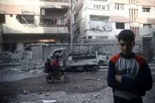 Children ride on a bicycle at a damaged site after an airstrike in the besieged town of Douma, Eastern Ghouta, Damascus, Syria, February 9, 2018. PHOTO BY REUTERS/Bassam Khabieh