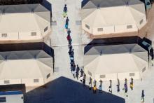 Immigrant children walk in single file between tents in their compound next to the Mexican border in Tornillo, Texas, June 18, 2018. PHOTO BY REUTERS/Mike Blake