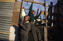 Lutando Gxotelwa, 12, climbs on wooden framing outside the family shack as Thina Gxotelwa, 6, children orphaned by AIDS, in Cape Town's Khayelitsha township, February 24, 2010. PHOTO BY REUTERS/Finbarr O'Reilly