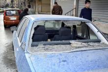 People walk past a damaged car after six mortar bombs landed in the Jaramana district of southeast Damascus. October 31, 2013. PHOTO BY REUTERS/SANA/Handout via Reuters