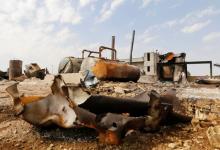 Men walk among debris at an oil refinery and a gas station that were targeted by what activists said were U.S.-led air strikes, in the town of Tel Abyad of Raqqa governorate, near the border with Turkey, October 2, 2014. PHOTO BY REUTERS/Stringer