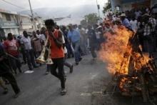 A protester playing two vuvuzelas walks next to a fire lighted for a ceremony during a demonstration against the government in Port-au-Prince, Haiti, January 25, 2016. PHOTO BY REUTERS/Andres Martinez Casares