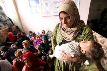 A displaced woman carries her child in a building that is used as a temporary shelter in Makhmour area, southeast of Mosul, Iraq, March 28, 2016. PHOTO BY REUTERS/Azad Lashkari