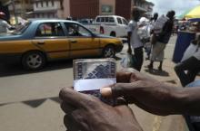 A street money changer or 'Dollar Boy' holds a wad of local leone banknotes as he plies his trade on Siaka Stevens street in the heart of Sierra Leone's capital Freetown, June 9, 2011. PHOTO BY REUTERS/Simon Akam