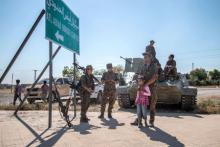 Fighters of the Kurdish People's Protection Units (YPG) stand with children near a sign in Tel Abyad town, Raqqa governorate, June 16, 2015. PHOTO BY REUTERS/Rodi Said