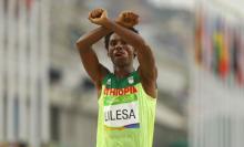 Feyisa Lilesa (ETH) of Ethiopia celebrates after the Final Men's Marathon in Rio de Janeiro, Brazil, August 21, 2016. PHOTO BY REUTERS/Athit Perawongmetha