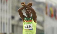Feyisa Lilesa (ETH) of Ethiopia celebrates after the Final Men's Marathon in Rio de Janeiro, Brazil, August 21, 2016. PHOTO BY REUTERS/Athit Perawongmetha