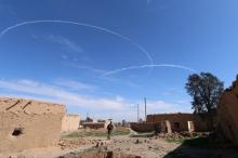 A Syria Democratic Forces fighter walks under contrails made by U.S. alliance air forces on the outskirts of al-Shadadi town, Hasaka countryside, Syria, February 19, 2016. PHOTO BY REUTERS/Rodi Said