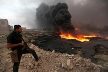 A member of the Iraqi security forces stands with his weapon as fire and smoke rise from oil wells, set ablaze by Islamic State militants before fleeing the oil-producing region of Qayyara, Iraq, which has been recaptured by Iraqi forces, August 29, 2016. PHOTO BY REUTERS/Azad Lashkari