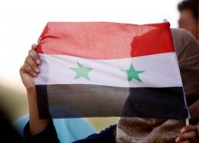 A woman holds a Syrian flag in Deraa, Syria, July 4, 2018. REUTERS/Omar Sanadiki/