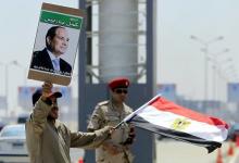 A man carrying a portrait of Egyptian President Abdel Fattah al-Sisi and an Egyptian flag stands next to a soldier during the funeral of Egyptian public prosecutor Hisham Barakat, on the second anniversary of the June 30 protests in Cairo, Egypt, June 30, 2015. PHOTO BY REUTERS/Mohamed Abd El Ghany